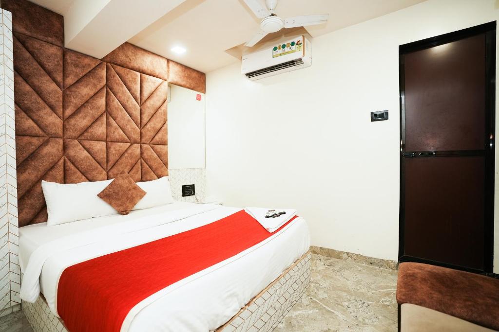 孟买HOTEL VERSOVA INN的一间卧室配有一张带红色毯子的床