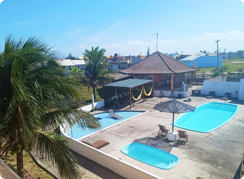 阿拉亚尔-杜卡布Villaggio dos Ventos的享有两个带椅子和遮阳伞的游泳池的上方景色