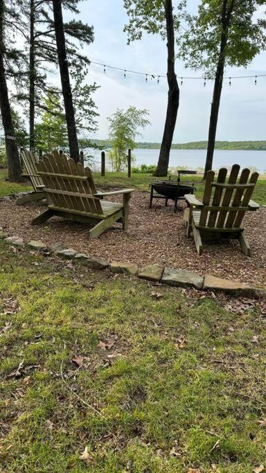 Heber SpringsCabin on the Lake的两根木凳坐在水边的草上