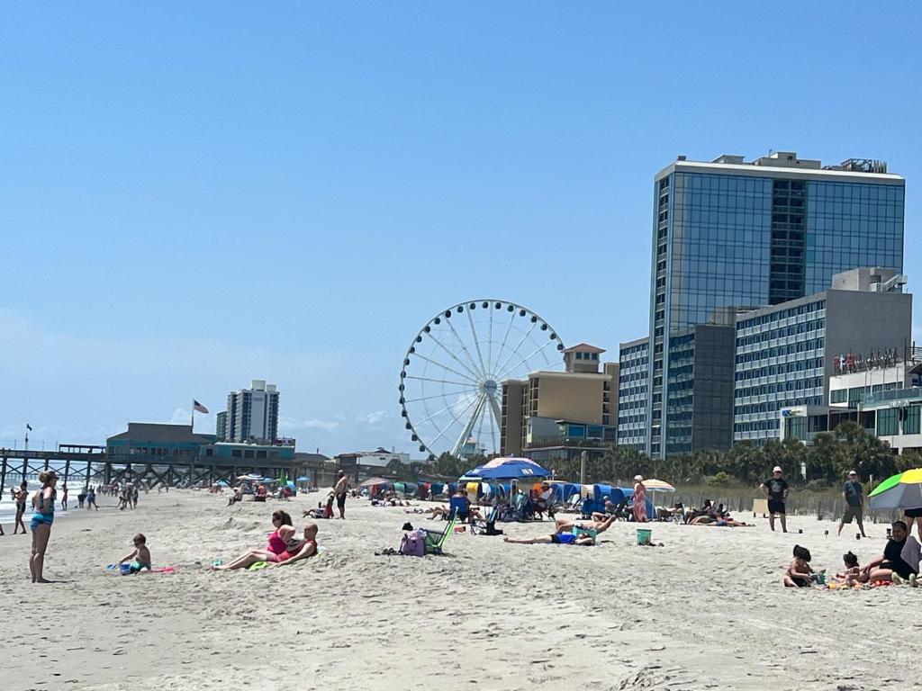 默特尔比奇Oceanfront 2BR King Suite Atlantica Resort的一群人坐在沙滩上,有摩天轮