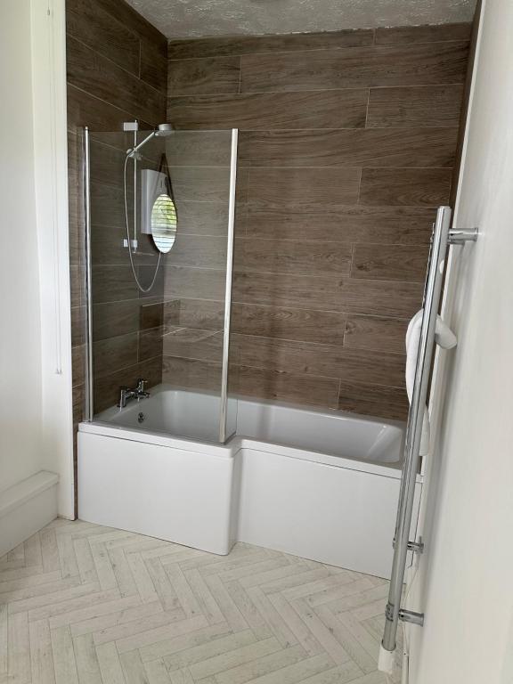 GulvalThe Coldstreamer的浴室配有白色浴缸和木墙