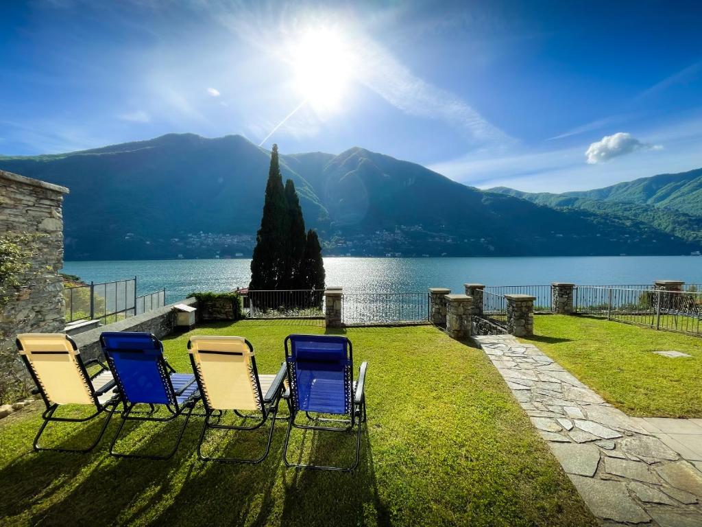 拉利奥Villa Luminosa Laglio - Private Parking, Garden的坐在湖边草地上的四把椅子