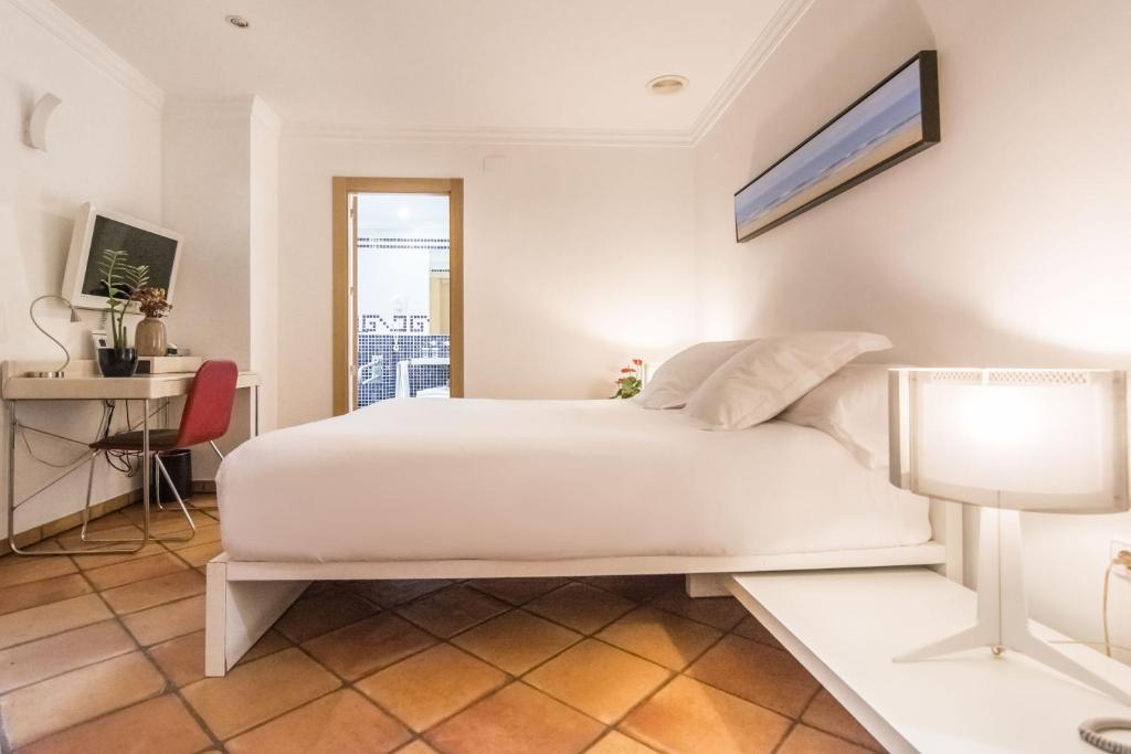 德尼亚Hotel Nou Romà的卧室配有一张白色大床和一张书桌