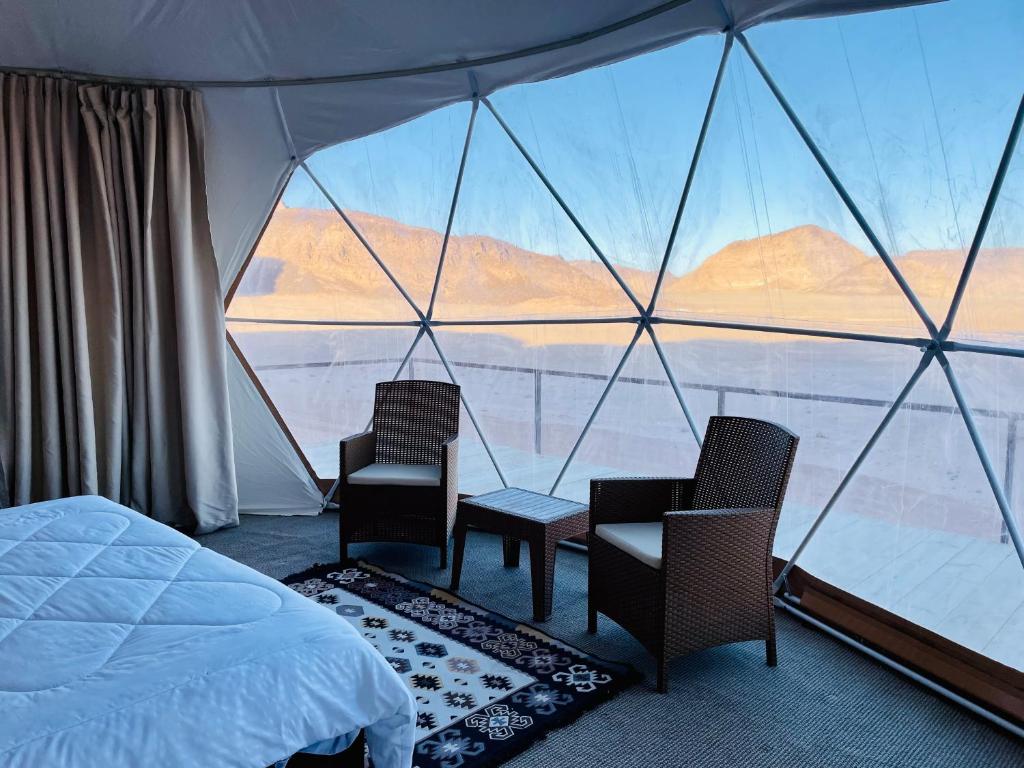 瓦迪拉姆Shaheen Camp Wadi rum的一间卧室配有一张床和两把椅子,并设有一个大窗户
