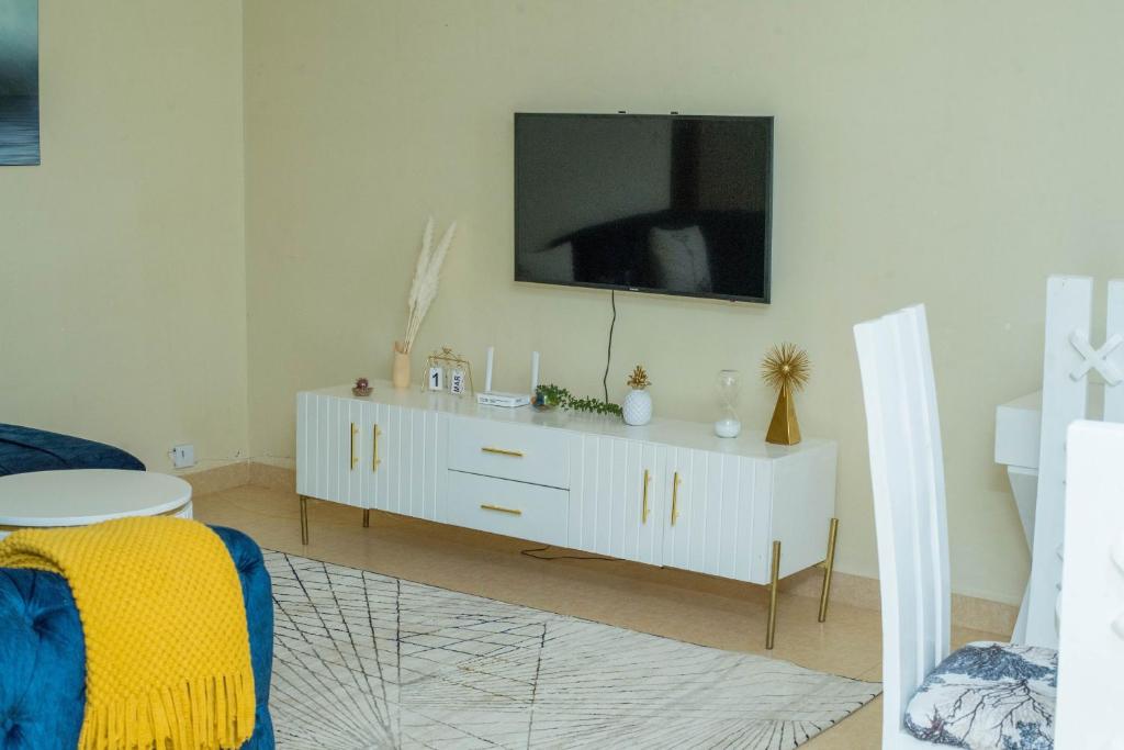 埃尔多雷特Eldoret home, Q10 unity homes的客厅配有白色橱柜和电视机
