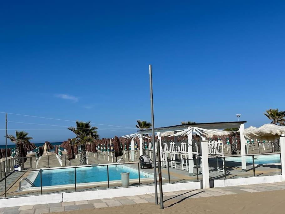 佩斯卡拉4 SEASON SUITES 130mq AD UN PASSO DAL MARE con GYM PRIVATA的一座带遮阳伞的游泳池,其背景是大海