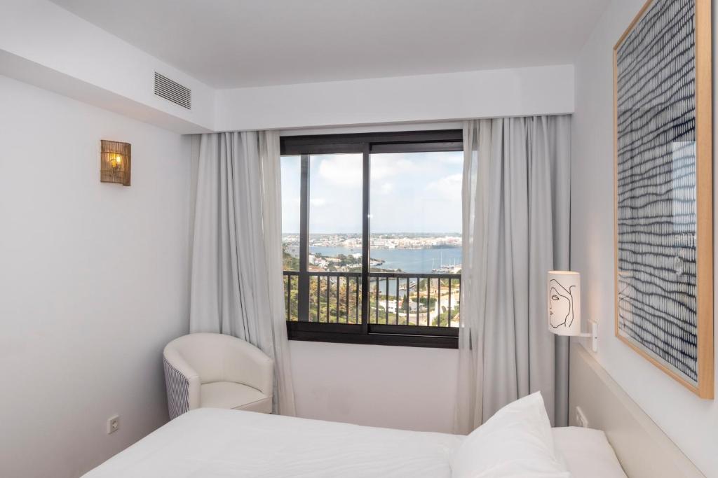 马翁Calallonga Hotel Menorca的酒店客房设有两张床和窗户。