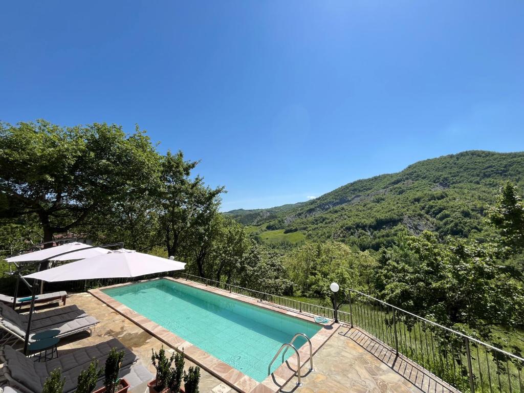ToanoVilla delle Fonti - Villa with pool的一座带遮阳伞和山脉的游泳池