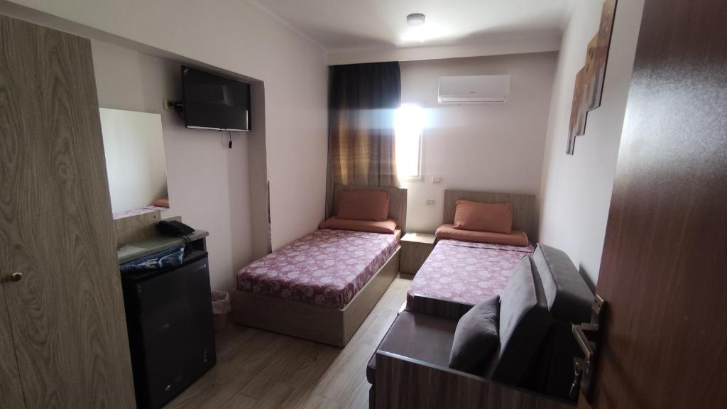 艾斯尤特فندق أجياد Agyad Hotel的小房间设有两张床和电视