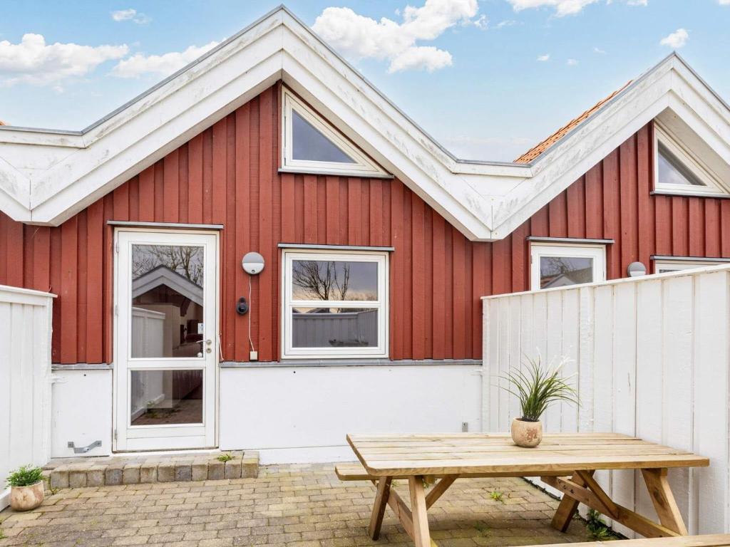 Nibe4 person holiday home in Nibe的一间红色的房子,配有白色的围栏和野餐桌