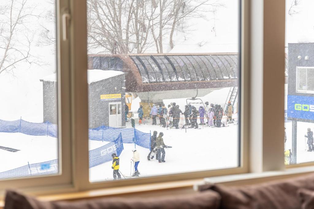 俱知安町Chalet Murasaki的窗户享有雪中人的景色