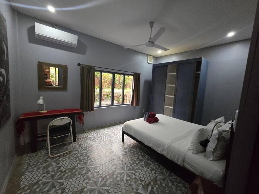 琅勃拉邦#5 Appartement meublé + piscine.的一间卧室配有一张床、一张书桌和一个窗户。