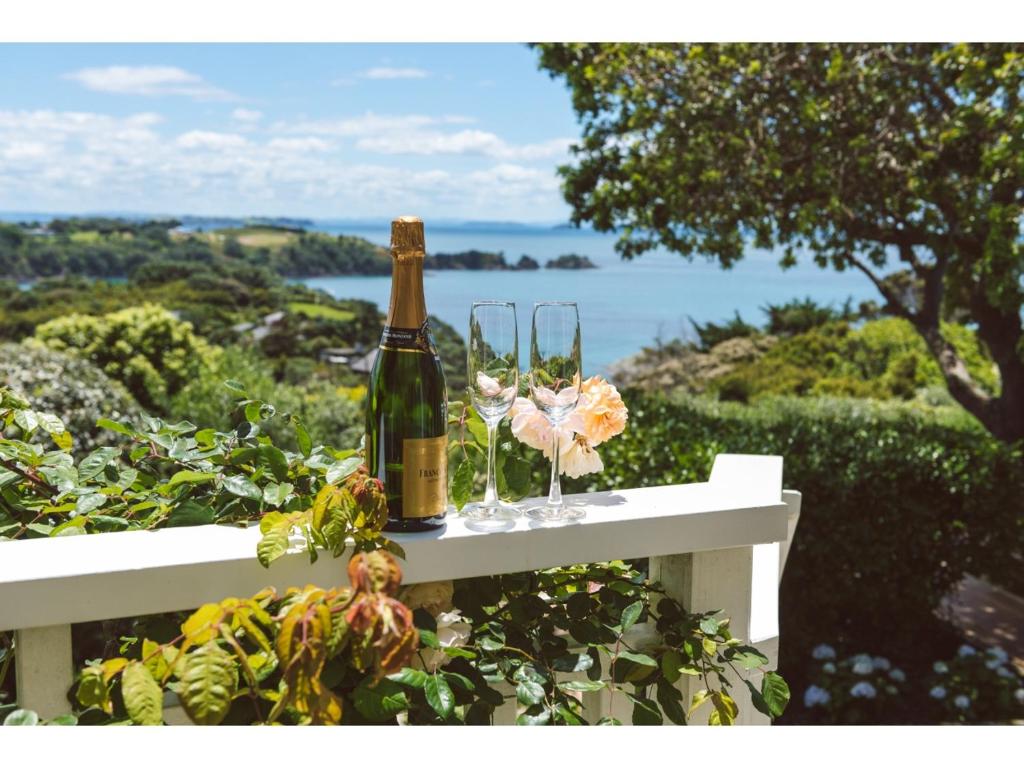 欧尼罗亚Romantic Cottage Recommended by NZ Herald的白色长凳上的一瓶香槟和玻璃杯