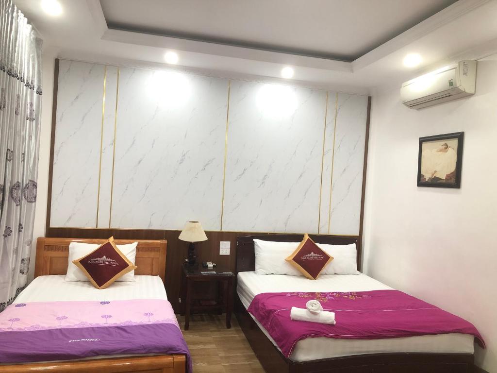 奠边府市Nhà nghỉ Như Ngọc的酒店客房设有两张床和一张桌子。