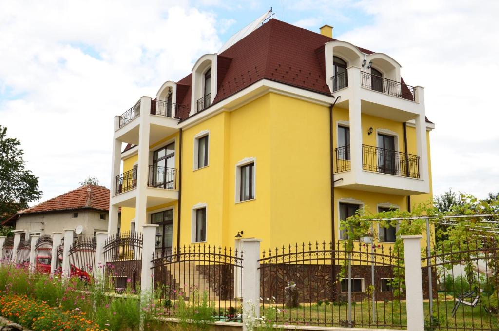 贝尔科维察Guest House Nocturno的黄色和白色的建筑,有红色屋顶