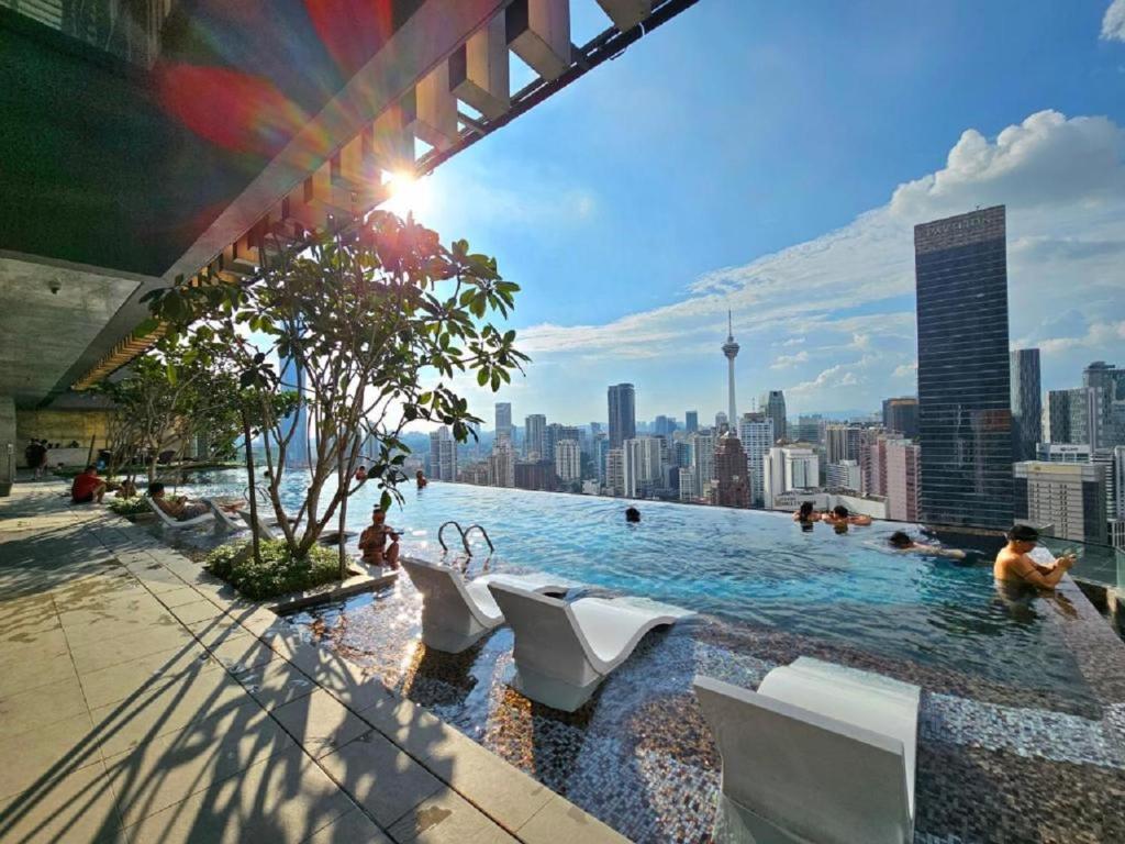 吉隆坡KL CITY CENTER AT AXON RESIDENCE的一个带白色椅子的游泳池,享有城市天际线