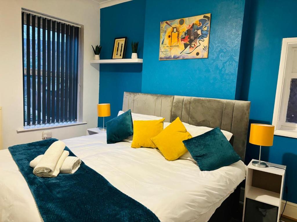 谢菲尔德HILLTOP PLACE SUITES near MEADOWHALL的一间卧室配有一张带蓝色墙壁和黄色枕头的床