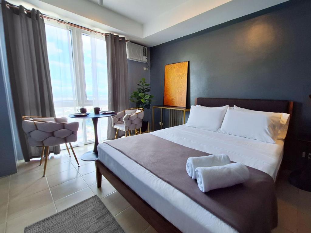 马尼拉ELUDE Designer Suite Pasig - Prime Location的一间卧室配有一张大床和一张桌椅