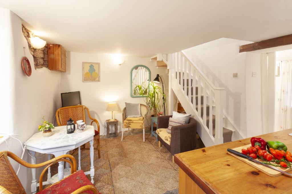 威弗利斯科姆Garden Cottage, Wiveliscombe的客厅设有楼梯和桌子,桌子上摆放着蔬菜
