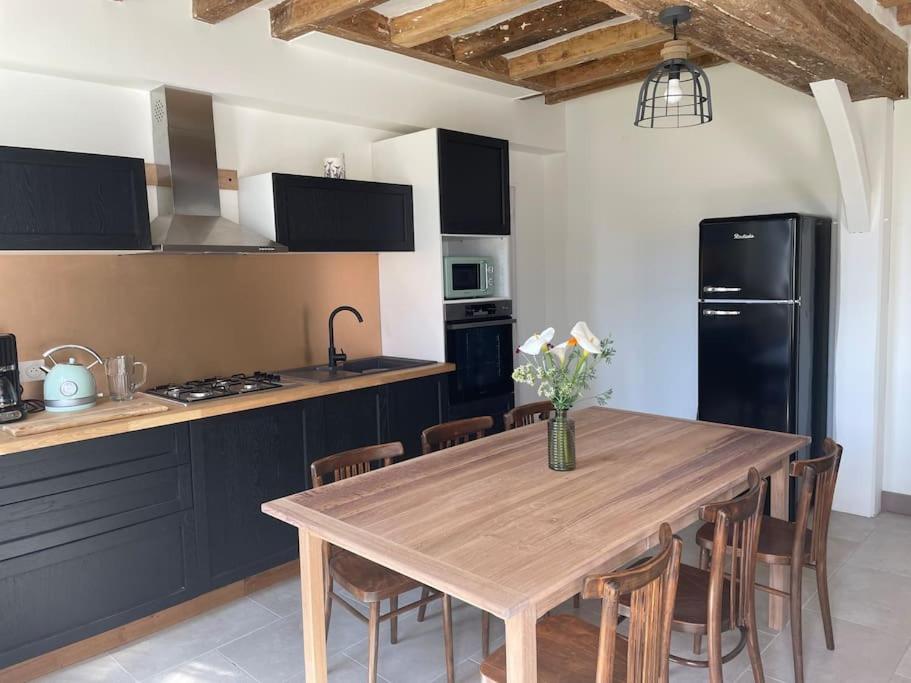 Saint-Clément-des-LevéesMaison bord de Loire的厨房配有木桌和黑冰箱。