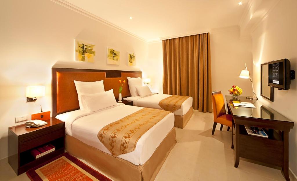 多哈Corp Hotel Apartments and Spa的酒店客房配有两张床和一张书桌