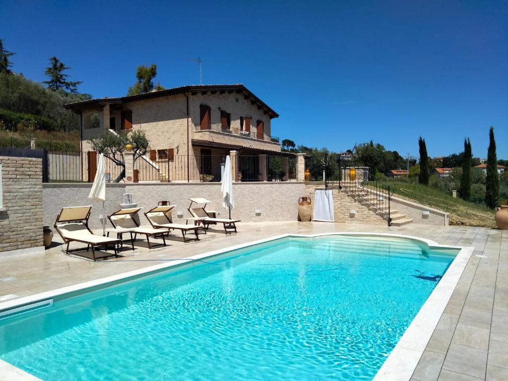SpinetoliB&B L' Antica Fonte的一个带椅子的游泳池和一个背景房子