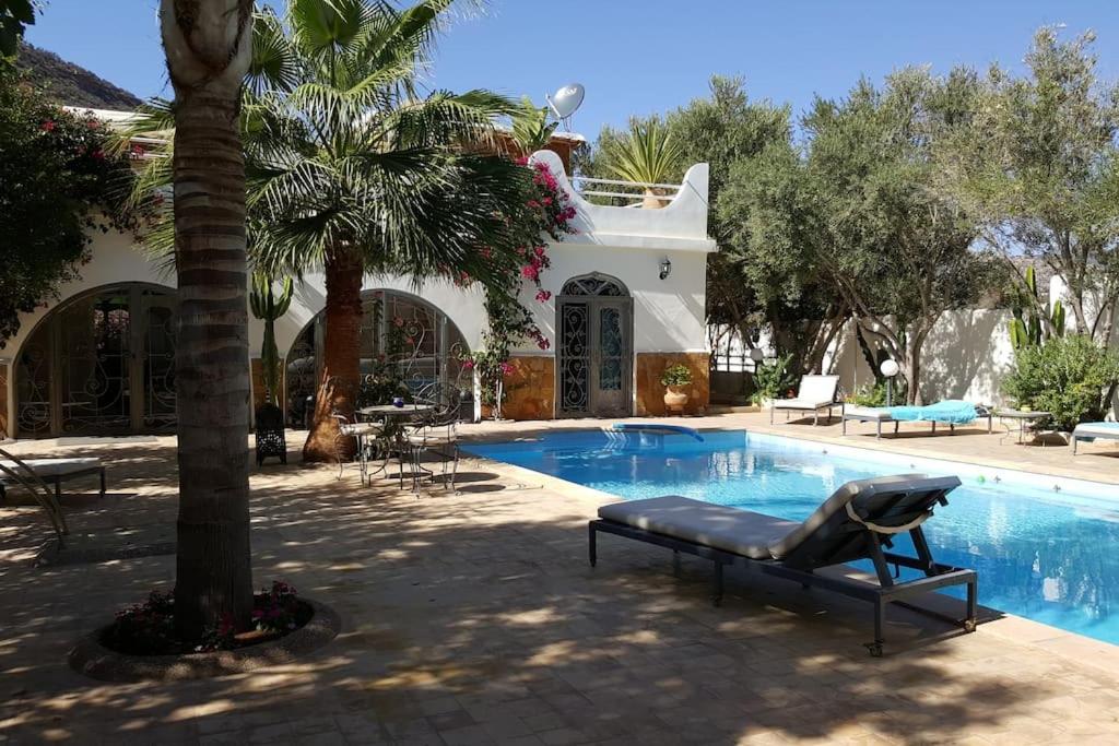 TagadirtVilla de charme, jardin paysagé, piscine privée的一个带游泳池和棕榈树的度假村