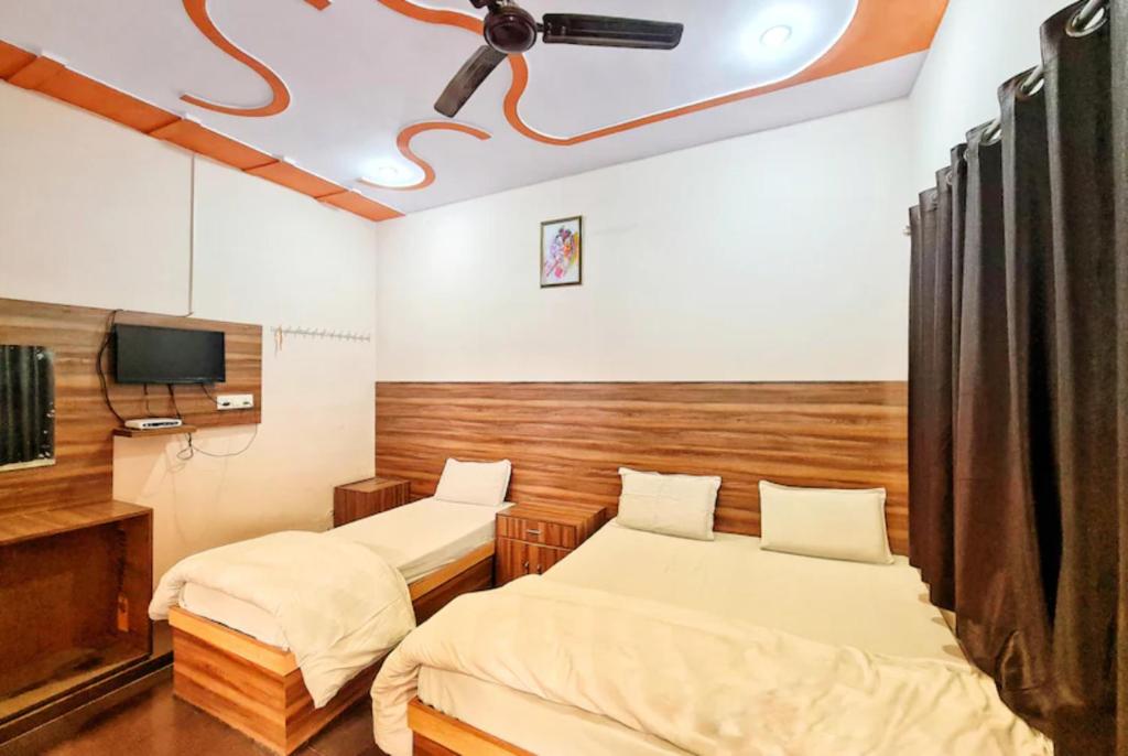 马图拉Goroomgo Sangam Palace Guest house Mathura - Prime Location的一间设有两张床和一台电视的房间