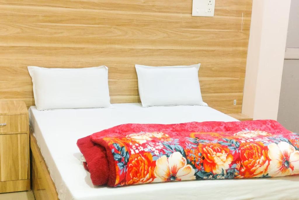 马图拉Goroomgo Sangam Palace Guest house Mathura - Prime Location的床上有五颜六色的毯子,有两个枕头