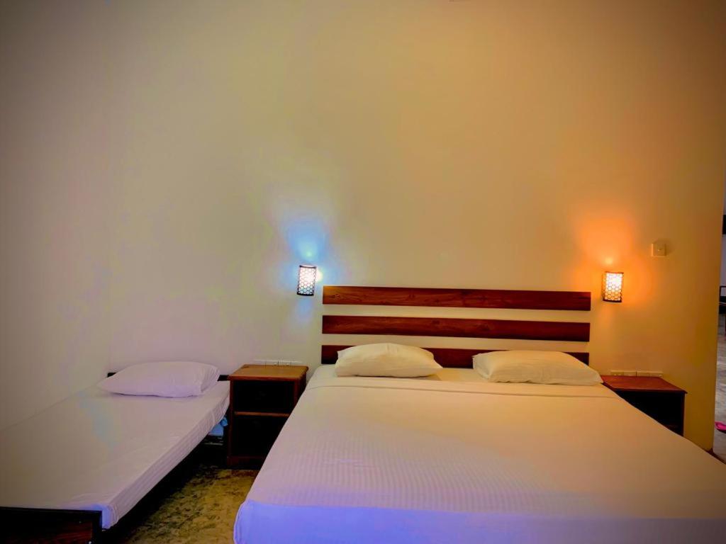 库鲁内格勒Raddagoda walawwa Hottel的一间卧室配有两张床,墙上有两盏灯