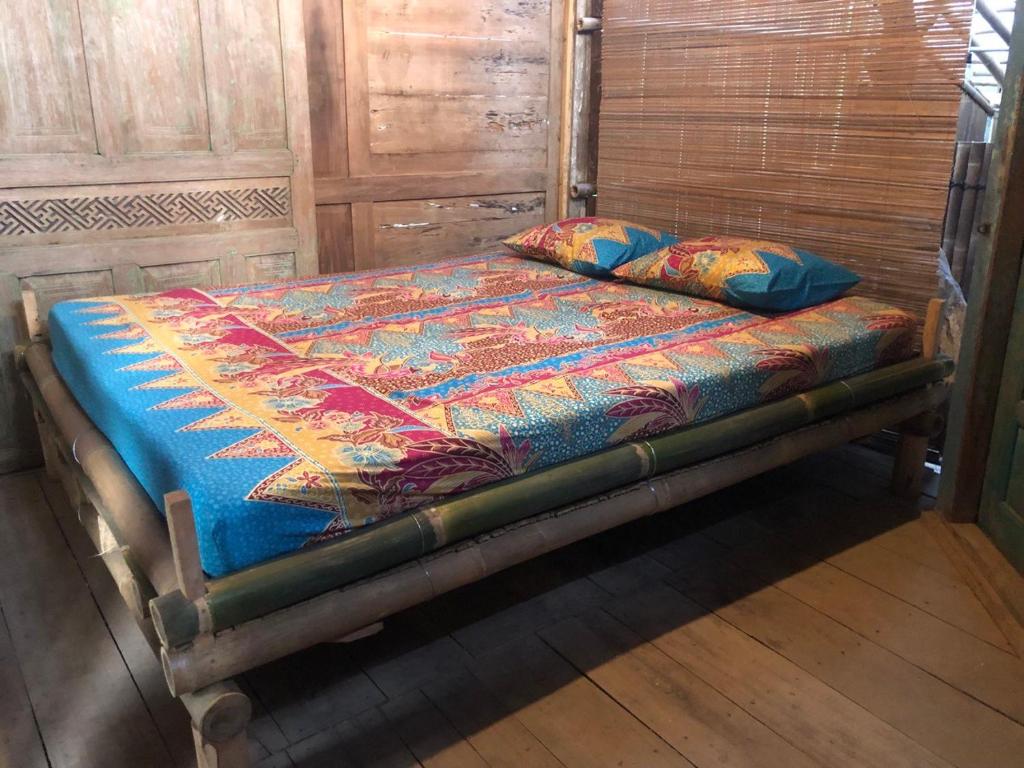 JarakanOmah Guyub 2的一张带色彩缤纷的被子和枕头的旧床