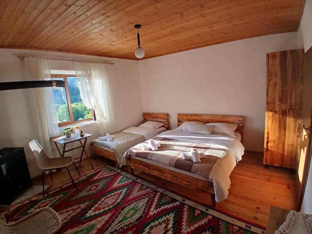 地拉那Bujtina Tusha的一间卧室设有两张床、一张桌子和一个窗口