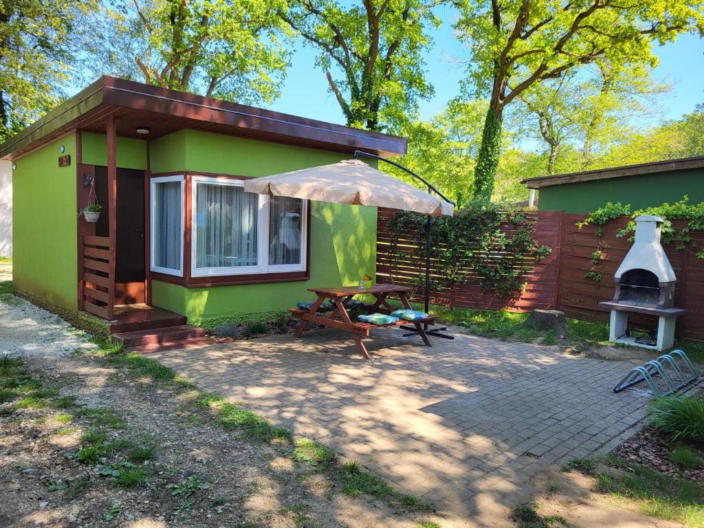 米利奇Szpak i Gil - domki letniskowe w Dolinie Baryczy的一座带野餐桌和雨伞的绿色小房子