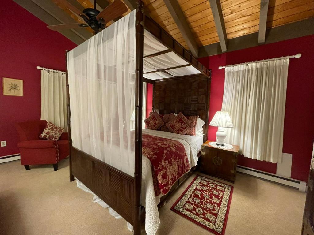 西多佛鹿茵宾馆的一间卧室设有天蓬床和红色的墙壁