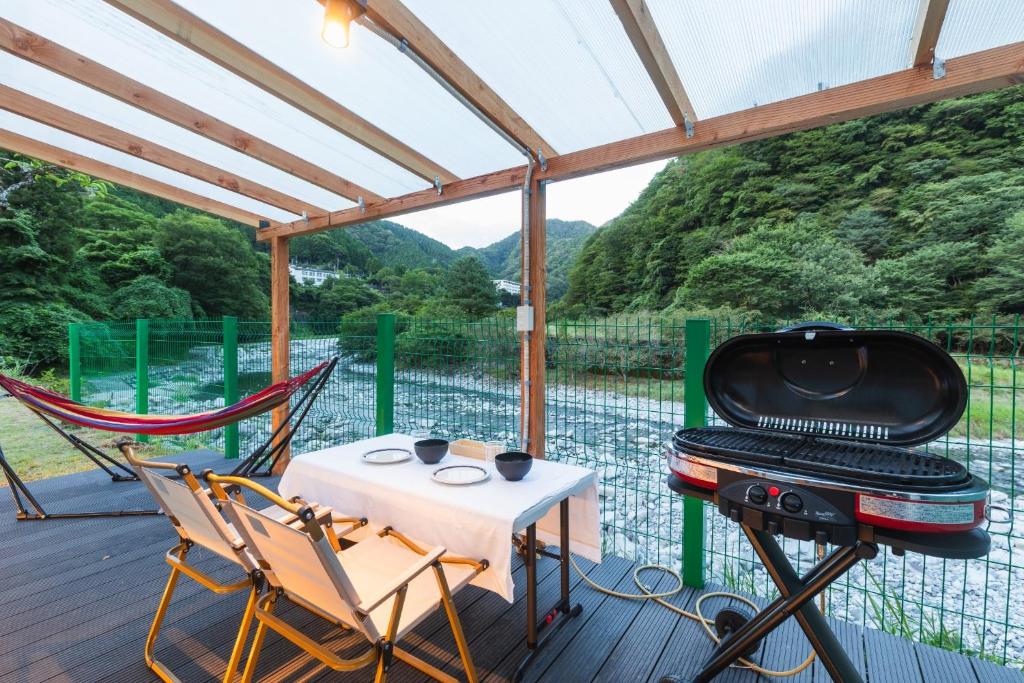 OyamaSPRINGS VILLAGE Ashigara-Tanzawa Hot Spring Resort & Glamping - Vacation STAY 42312v的门廊设有烧烤架、桌子和椅子