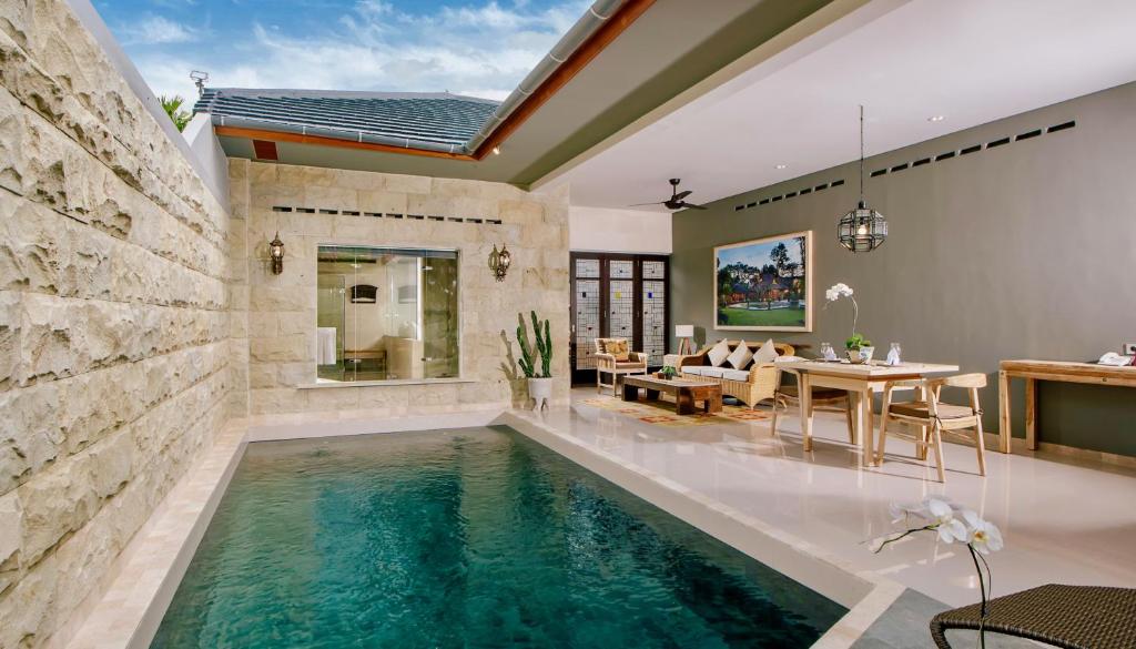 努沙杜瓦Alindra Villas & Spa的客厅中央的游泳池,带饭厅