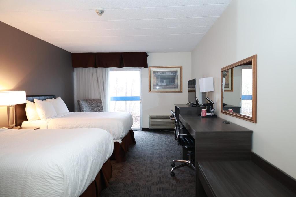 萨德伯里Days Inn by Wyndham Sudbury & Conference Centre的酒店客房配有两张床和一张带镜子的书桌