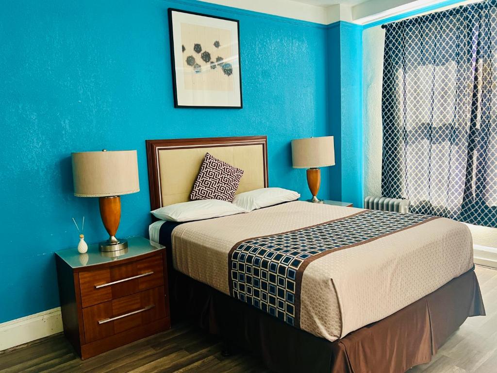 旧金山海军上将酒店的一间卧室配有一张蓝色墙壁的床和两盏灯。