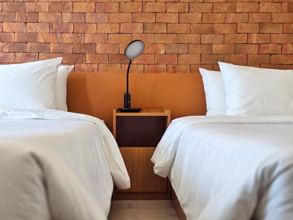 彭世洛Wangkaew Hotel的一间卧室配有两张床和床头灯。