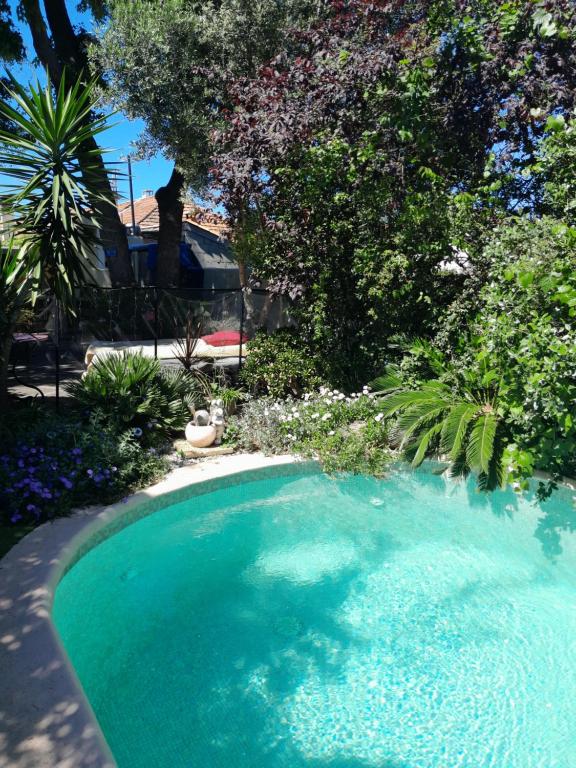 马赛APPARTEMENT EN SOUS SOL DE VILLA avec accès jardin et piscine的一座种有树木和鲜花的庭院内的游泳池