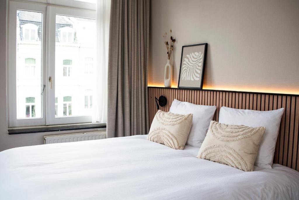 马斯特里赫特波什斯坦什伯格酒店的卧室配有一张带白色床单和枕头的大床。