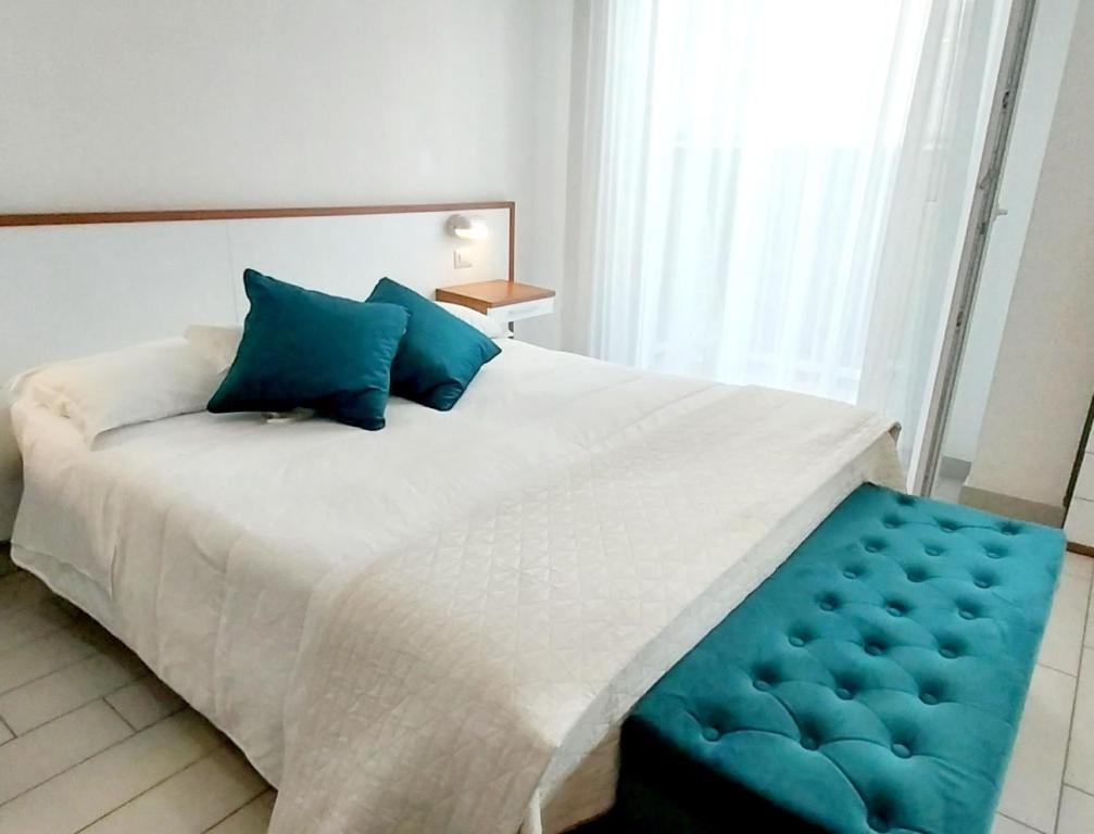里米尼布罗塔斯酒店的卧室配有带蓝色枕头的大型白色床