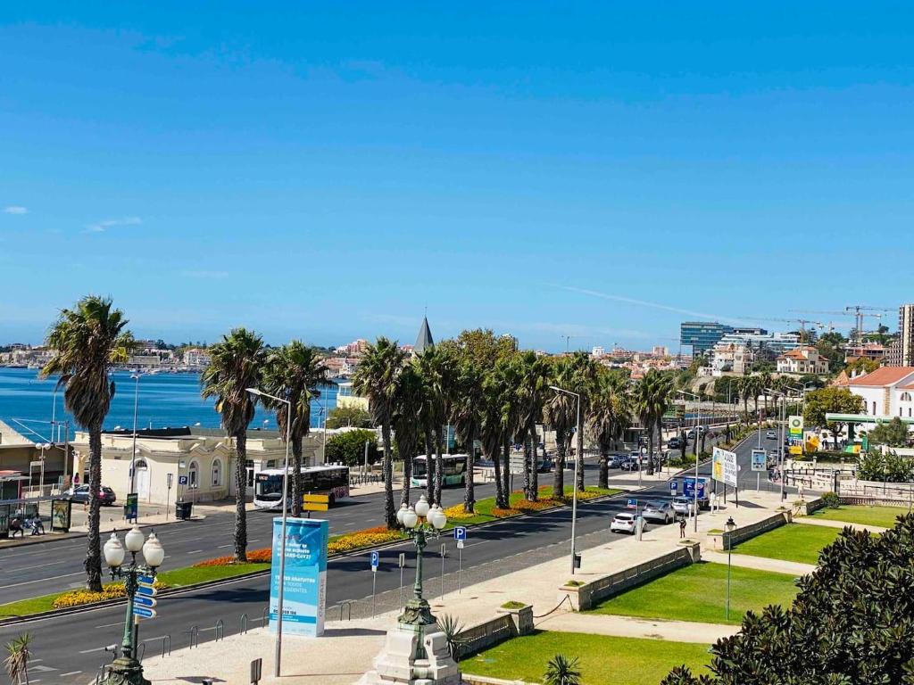 埃斯托利尔Sea View 2 Mins Walk To Beach And Estoril Casino的一条种满棕榈树的城市街道和一条有汽车的街道