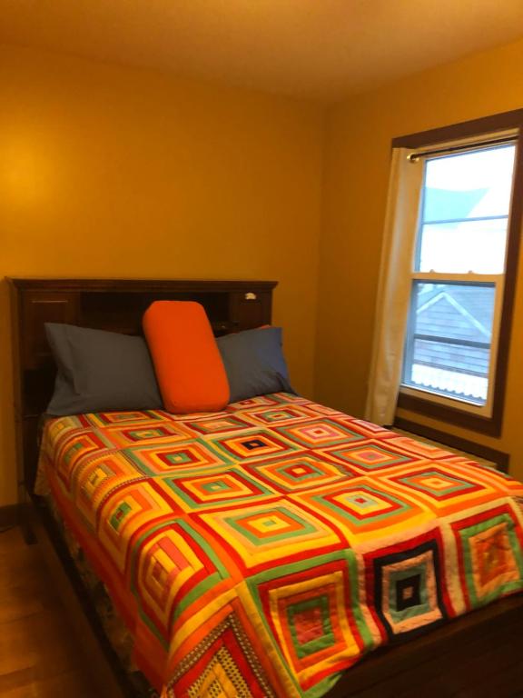 South Ozone ParkRoom to stay in的一间卧室配有一张带橙色枕头的床和窗户