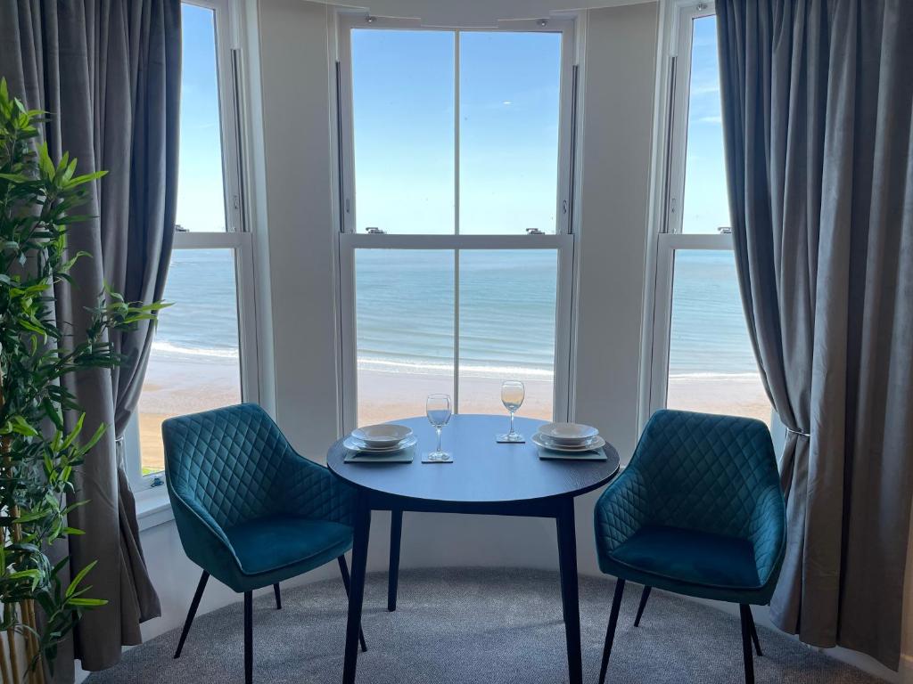 斯卡伯勒The Marlborough Sea View Holiday Apartments的一间带桌子和两把椅子的用餐室以及窗户。