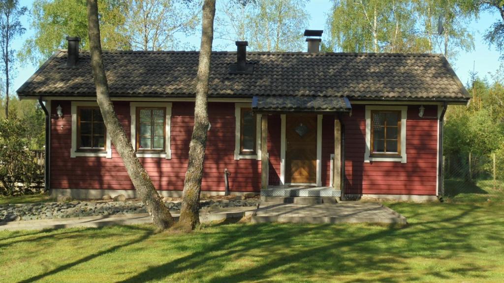 海斯勒霍尔姆Minnebo stuga的前面有树木的红房子
