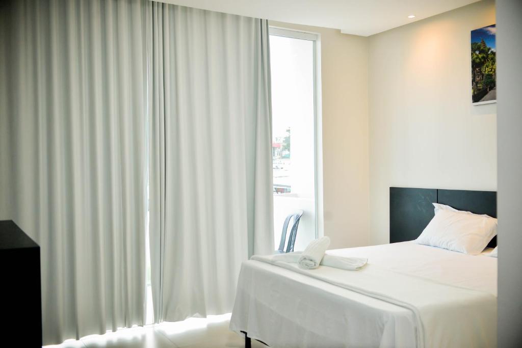 阿拉皮拉卡hotel quatro coracoes的白色的卧室设有床和窗户