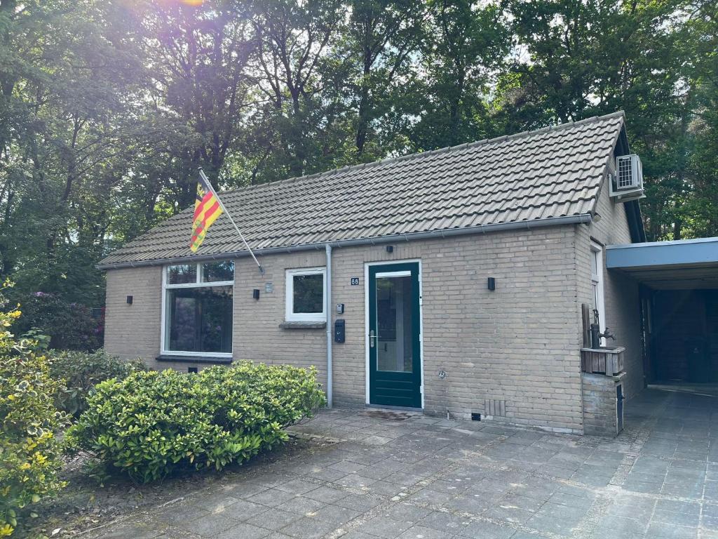 拉克斯杰斯特Boshuis Luyksgestel 2-6 personen, veel privacy!的前面有旗帜的小房子
