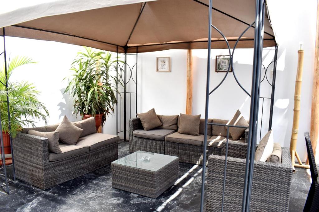 帕拉卡斯Hospedaje El Buen Samaritano的天井配有2张沙发和1把遮阳伞。