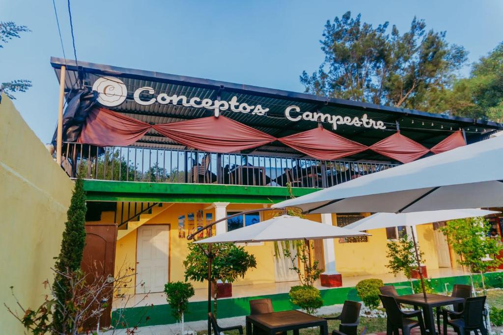 韦韦特南戈Conceptos Campestre的大楼前的咖啡馆,带桌子和遮阳伞